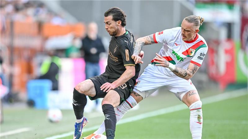 Augsburg Marius Wolf (r) nimmt dem Gladbacher Joe Scally den Ball ab.