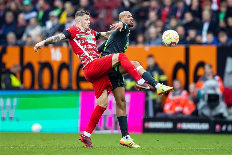 Gouweleeuw genervt: Siebert erläutert Entscheidungen Augsburgs Jeffrey Gouweleeuw (l) in Aktion gegen Wolfsburgs Lukas Nmecha (r).