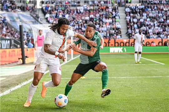 Augsburgs Kevin Mbabu (l) in Aktion gegen Bremens Felix Agu (r).