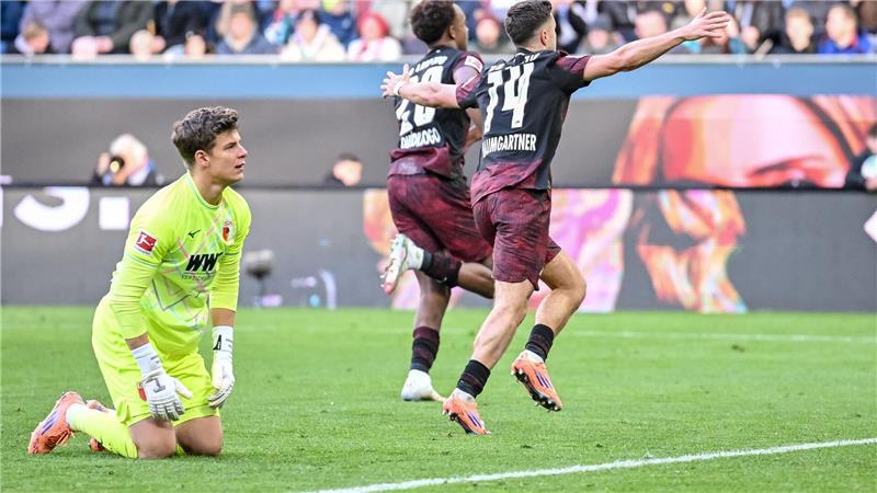 Junge Leipziger Turbo-Kicker führen naive Wagner-Elf vor Augsburgs Torwart Finn Dahmen kauert bedröppelt am Boden, die Leipziger Assan Quedraogo (M) und Christoph Baumgartner (r) bejubeln das 0:5.
