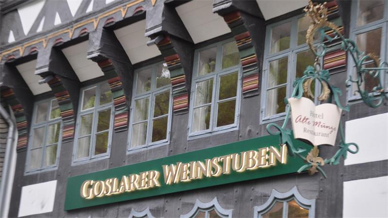 Fachwerkhausfassade mit mehreren Fenstern und einem grünen Schild mit goldener Aufschrift 'GOSLARER WEINSTUBEN'