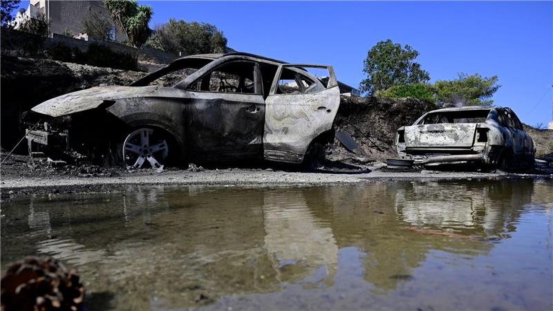 Ausgebrannte Autos spiegeln sich im Wasser nach einem Waldbrand in dem Dorf südöstlich von Athen. 