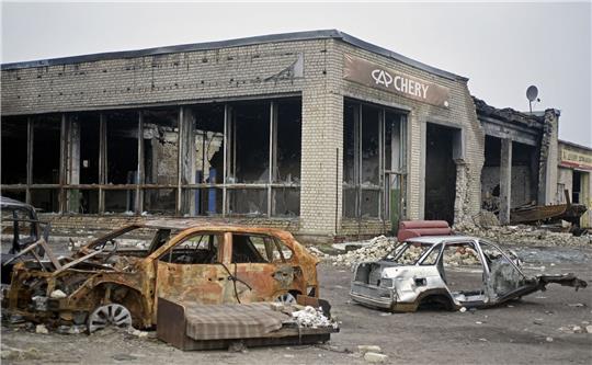 Ausgebrannte Autos stehen vor einem Autohaus, das durch russischen Beschuss in Isjum zerstört wurde.