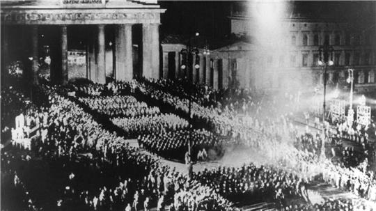 Authentischer SA-Fackelzug für den „Führer“? Mitnichten. Das Archivbild aus dem Sommer 1933 zeigt eine für einen Nazi-Film nachgestellte Szene des Marsches durch das Brandenburger Tor, mit dem die Nationalsozialisten am 30. Januar 1933 die Machtübernahme feierten.