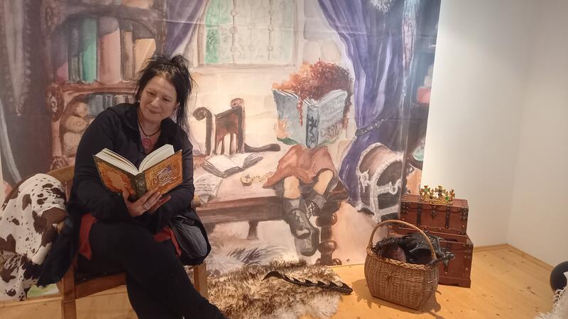 Fantasy-Lesung im Goslarer Mönchehaus lockt 70 Drachen-Fans an Autorin Ute Augstein "sitzt in ihrem Buch": Das Bild im Hintergrund ist eine vergrößerte Darstellung einer Illustration, die die Künstlerin Tanja Ulrich für das Drachen-Abenteuer angefertigt hat.