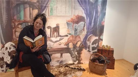 Autorin Ute Augstein "sitzt in ihrem Buch": Das Bild im Hintergrund ist eine vergrößerte Darstellung einer Illustration, die die Künstlerin Tanja Ulrich für das Drachen-Abenteuer angefertigt hat.