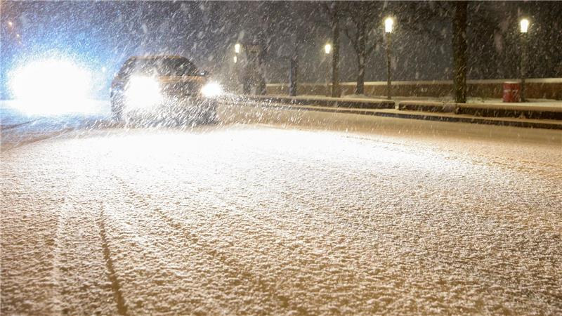 Autos fahren auf einer schneebedeckten Straße in Hamburg.