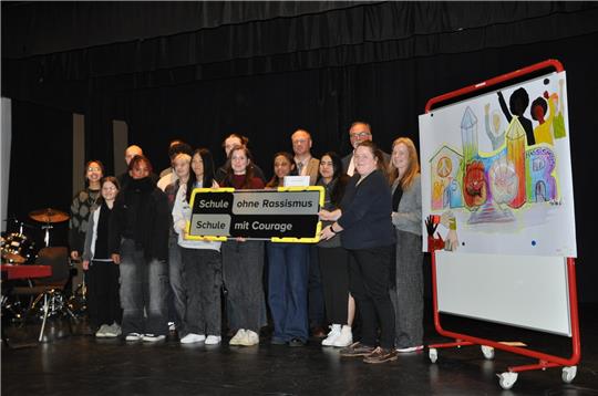 Awo-Chefin Tjorven Maack (2.v.r) überreicht das offizielle Schild an die RG-Schulgemeinschaft. Foto: Heine