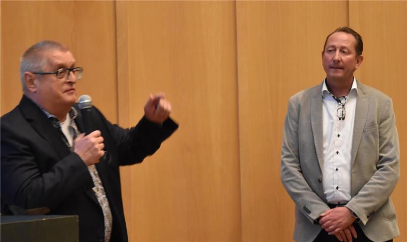 Zwei Männer, einer redet in ein Mikro, der andere hört zu.