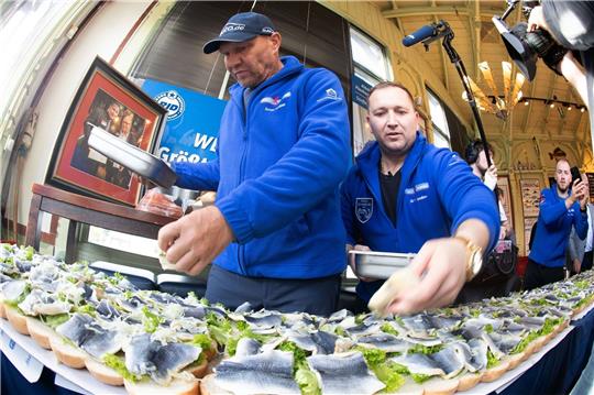 Axel Schulz, ehemalige Profiboxer (l-r), und André Domke Fischsommelier und Fischhändler belegen das gigantische Fischbrötchen mit Salat, Fisch und Zwiebeln.