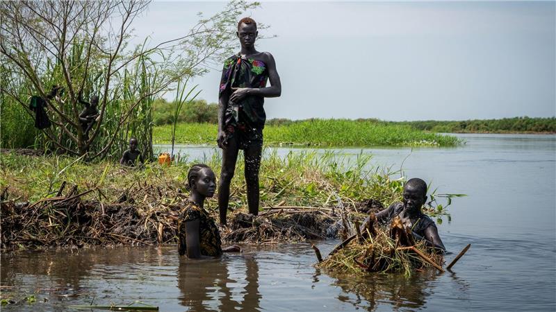 Ayen Deng Duot (r) und ihre Familie befestigen ihre Insel mit Pflanzen und Schlamm aus dem Sumpf, um zu verhindern, dass ihr Haus am Nil überflutet wird.