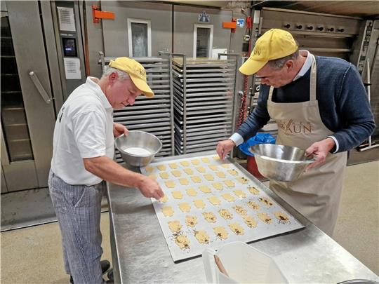 Bäckermeister Jürgen Braun und sein Praktikant Jörg Kleine verzieren die Schweineplätzchen..