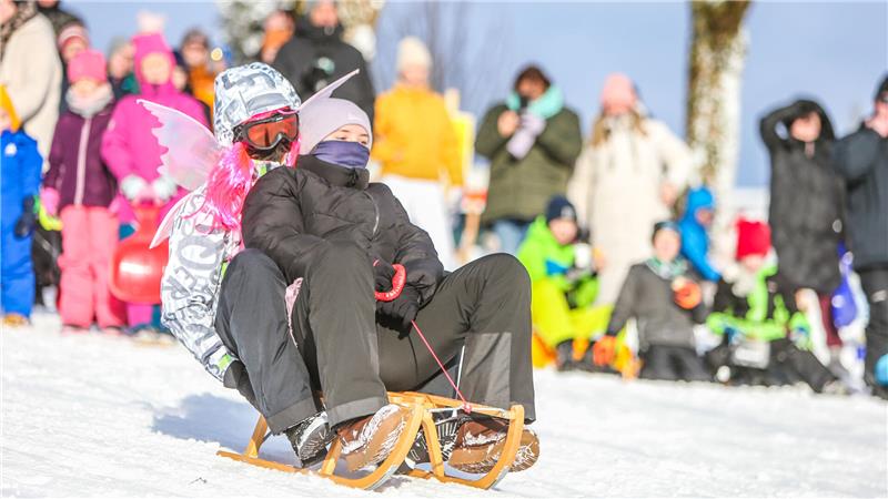 Zwei Menschen rodeln zu zweit auf einem Schlitten.
