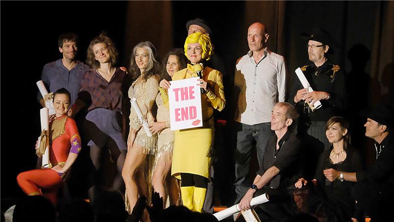 „Bartuschka“ (Mitte) versammelt zum Abschlussbild der Langen Nächte der Kleinkunst noch einmal alle Akteurinnen und Akteure um sich herum zum Gruppenbild auf der Bühne.