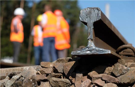 Bauarbeiter stehen auf einer Baustelle am Bahnknoten Dessau-Roßlau.