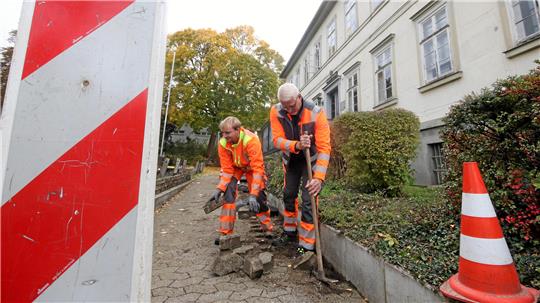 Bauhofmitarbeiter nehmen am Fußweg zum Haupteingang des Liebenburger Rathauses das Pflaster auf.