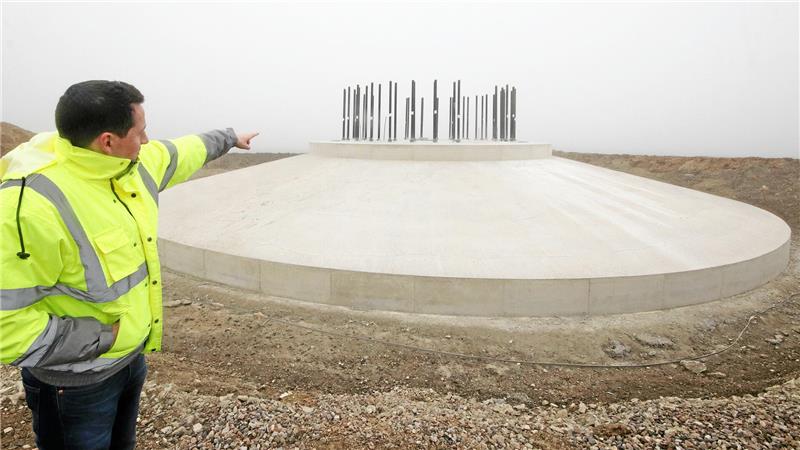 Bauleiter Jan Zimmer deutet auf ein fertig gegossenes Fundament. Oben ragen 24 Spannglieder heraus, auf denen die weitere Anlage errichtet wird.