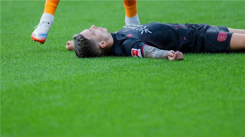 Bayer Leverkusens Kapitän Alejandro Grimaldo liegt nach einem Zusammenprall mit dem eigenen Mann benommen auf dem Boden. 