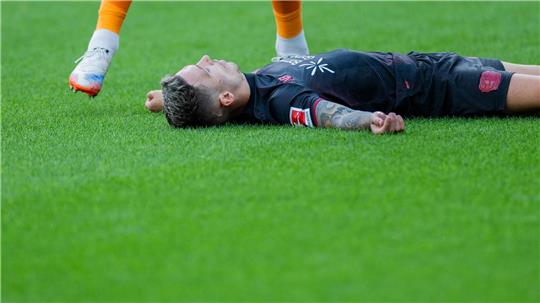 Bayer Leverkusens Kapitän Alejandro Grimaldo liegt nach einem Zusammenprall mit dem eigenen Mann benommen auf dem Boden. 