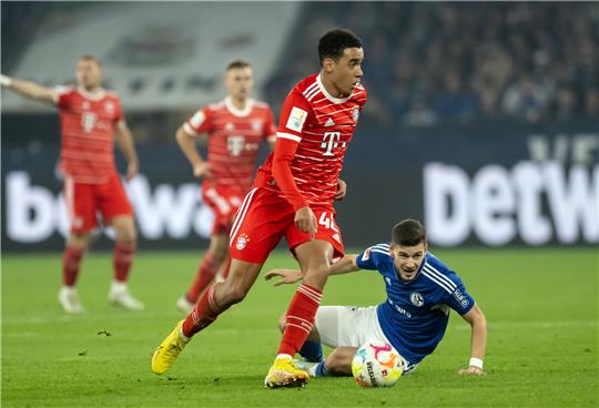 Bayern Münchens Jamal Musiala (Mitte) zauberte auch gegen Schalke, Gegenspieler Tom Krauß kann hier nur zuschauen. Foto: Bernd Thissen/dpa