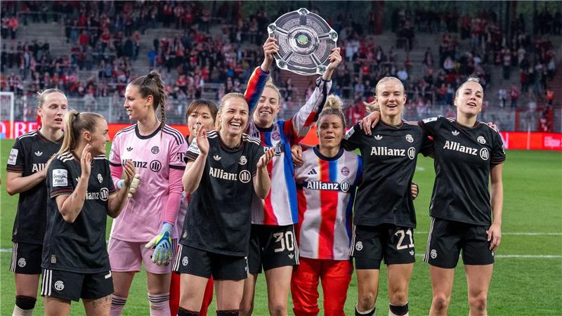 Bayern Münchens Spielerinnen jubeln nach dem Spiel gegen den 1. FC Union Berlin mit der Nachbildung einer Meisterschale über den Sieg.