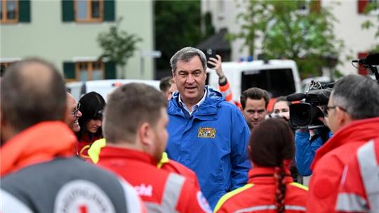 Bayerns Ministerpräsident Markus Söder (M, CSU), spricht zu Einsatzkräften vom Roten Kreuz, DLRG und anderen Rettungskräften bei einer Ortsbesichtigung im vom Hochwasser betroffenen oberbayerischen Reichertshofen.