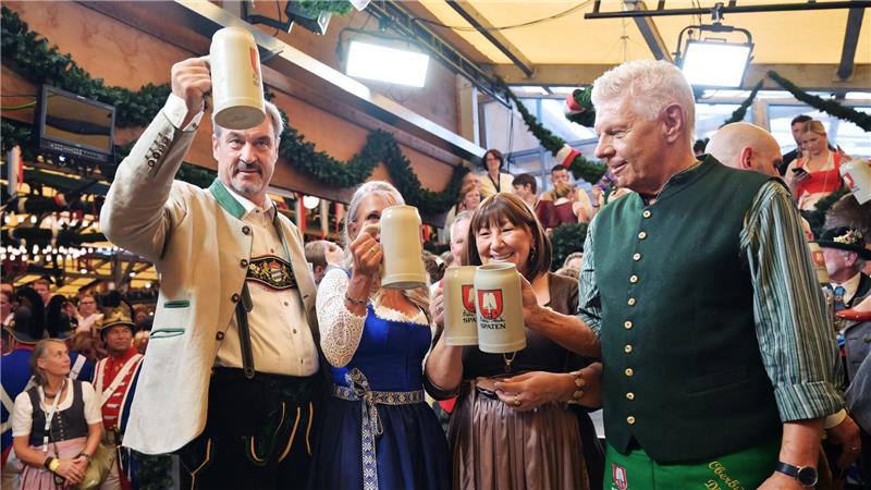 Bayerns Ministerpräsident Söder (l.) und Münchens OB Reiter (r.) stoßen mit ihren Ehefrauen auf eine friedliche Wiesn an.