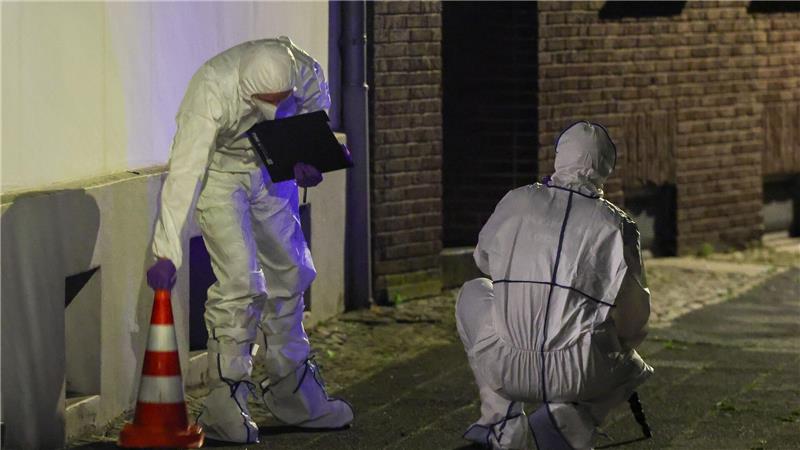Beamte der Spurensicherung in Spurensicherungsanzügen begutachten den Tatort.