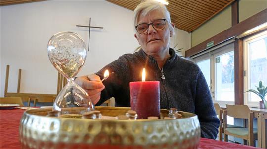 Eine Frau zündet eine Kerze an.