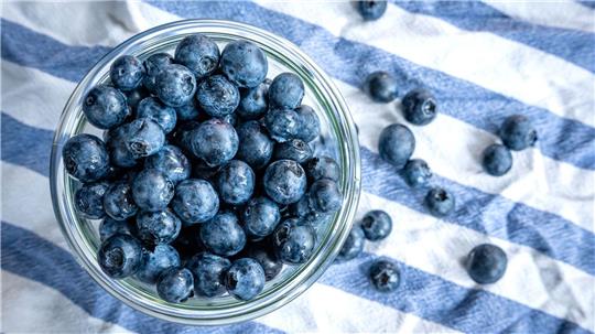 Beeren statt Chips oder Nüsschen: Heidelbeeren, auch Blaubeeren genannt, liegen auf einem Esstisch und werden gern gesnackt.
