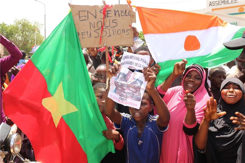 Befürworter des Putschs halten eine Flagge von Burkina Faso (l) und Niger hoch. Die beiden Länder haben einen Pakt geschlossen.