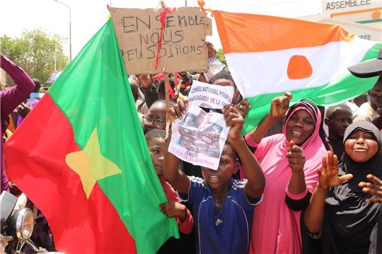 Befürworter des Putschs halten eine Flagge von Burkina Faso (l) und Niger hoch. Die beiden Länder haben einen Pakt geschlossen.