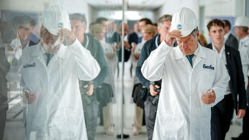 Habecks Charmeoffensive in Griechenland - Spitze gegen Merz Behelmt bei einem Firmenbesuch.