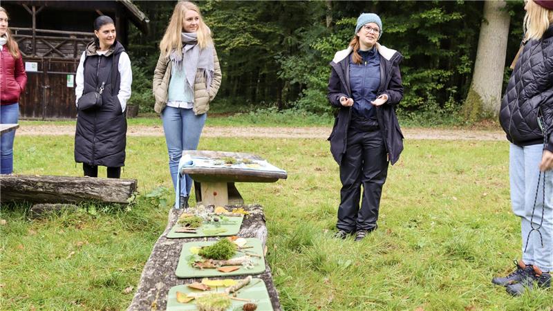 Lautenthalerin Jasmin Frommhold zeigt Wege zum Glück Fünf Frauen stehen am Waldrand auf einer Wiese beim Workshop mit Jasmin Frommhold. Im Vordergrund sindauf zwei Holzbänken grüne Brettchen mit Kräutern zu sehen.