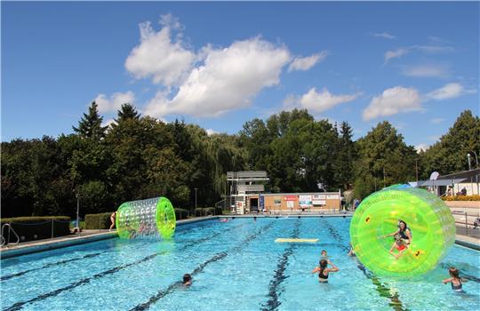 Bei Sommerfest im Stadtbad vergnügen sich Mädchen und Jungen mit den Wasserbällen. Die Badegäste können auch Unterwasserfotos von sich knipsen lassen. Foto: Hohaus