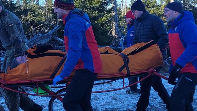 Mehrere Menschen transportieren eine verletzte Person auf einer sogenannten Rolltrage.
