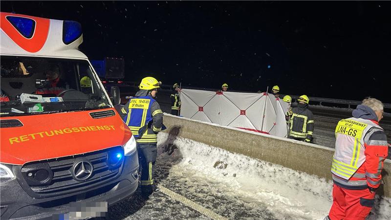 Ein Krankenwagen fährt nachts mit Blaulicht durch eine Straße.