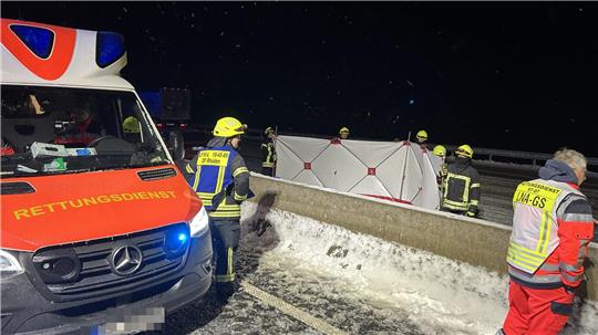 Ein Krankenwagen fährt nachts mit Blaulicht durch eine Straße.