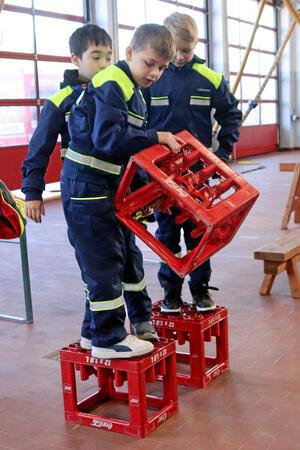 Drei Kinder versetzen Getränkekisten, über die sie gehen müssen.
