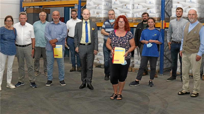 Gruppe von Menschen steht in einer Lagerhalle vor Regalen mit weißen Säcken