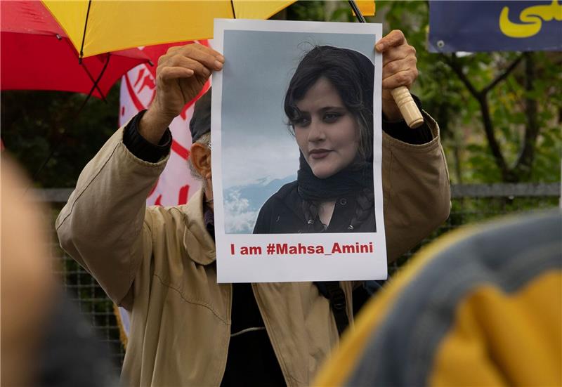 Bei einem Protest in Berlin hält ein Mann ein Bild der verstorbenen Mahsa Amini in Händen.