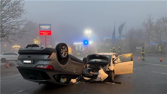 Zwei Autos sind zusammengestoßen. Ein Wagen steht auf dem Dach.