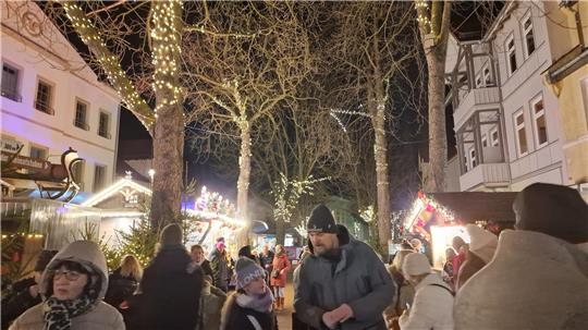 Menschen laufen durch die weihnachtlich beleuchtete Stadt.