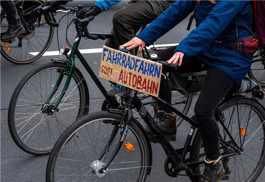 Bei einer Demo fährt ein Fahrradfahrer mit einem Schild mit der Aufschrift ««Fahrradfahr’n» statt Autobahn».