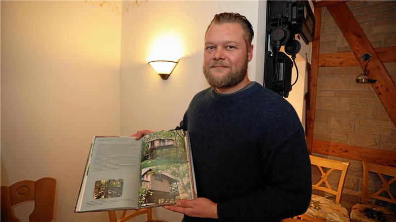 Bei einer Informationsveranstaltung im November 2023 zeigt Investor Robert Windaus in einem Buch, wie seine Baumhäuser im Zellerfelder Kurpark aussehen sollen.