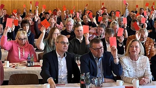 Ein voll besetzter Saal, die Menschen heben zur Abstimmung rote Karten.