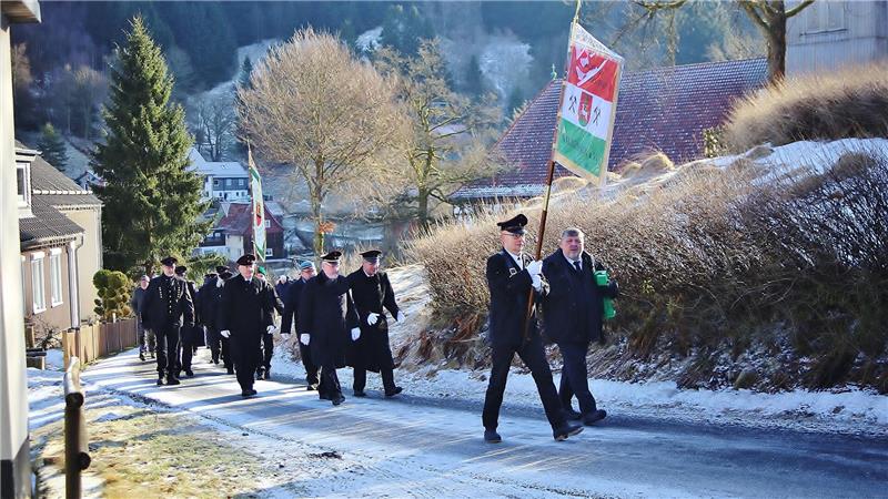 Bergdankfest im Oberharz: Tradition lebt trotz eisiger Kälte Mehrere Menschen marschieren in Uniform und teilweise mit Flaggen einen Hügel herauf.