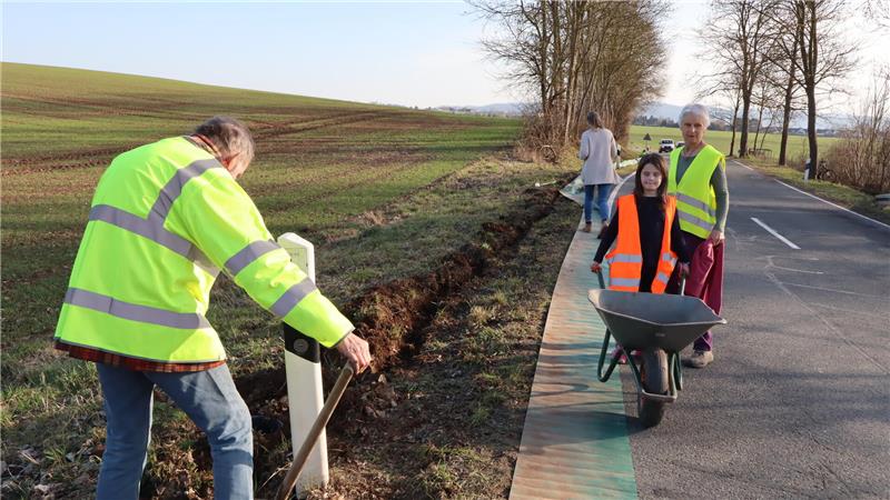 Mehrere Personen arbeiten an einer Landesstraße. 