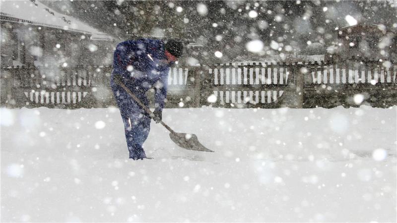 Ein Mann schiebt Schnee. 