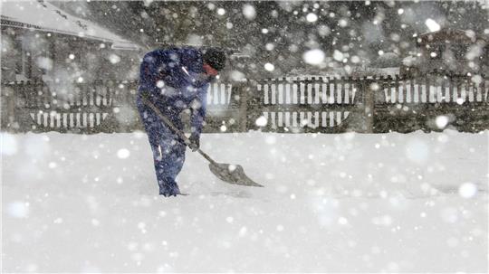 Ein Mann schiebt Schnee. 